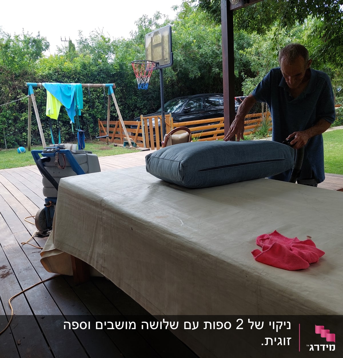 אדם מנקה כרית ספה עם שואב אבק בחצר